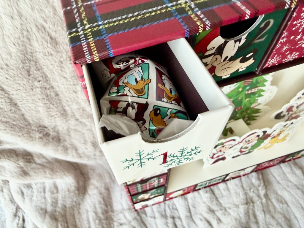1番の引き出しを開けて中身を確認する写真。ドナルド柄のアイテムが入っているディズニーストア アドベントカレンダー。