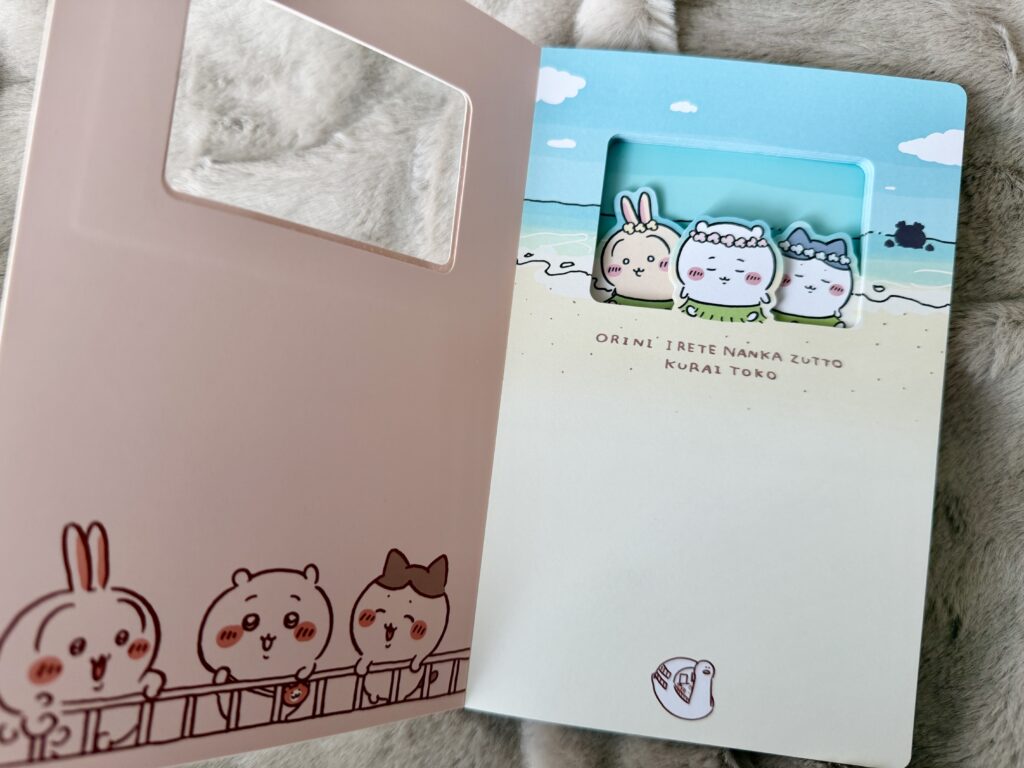 ピンクのノートを開いた状態で、海辺に立つちいかわたちの付箋がセットされている写真。