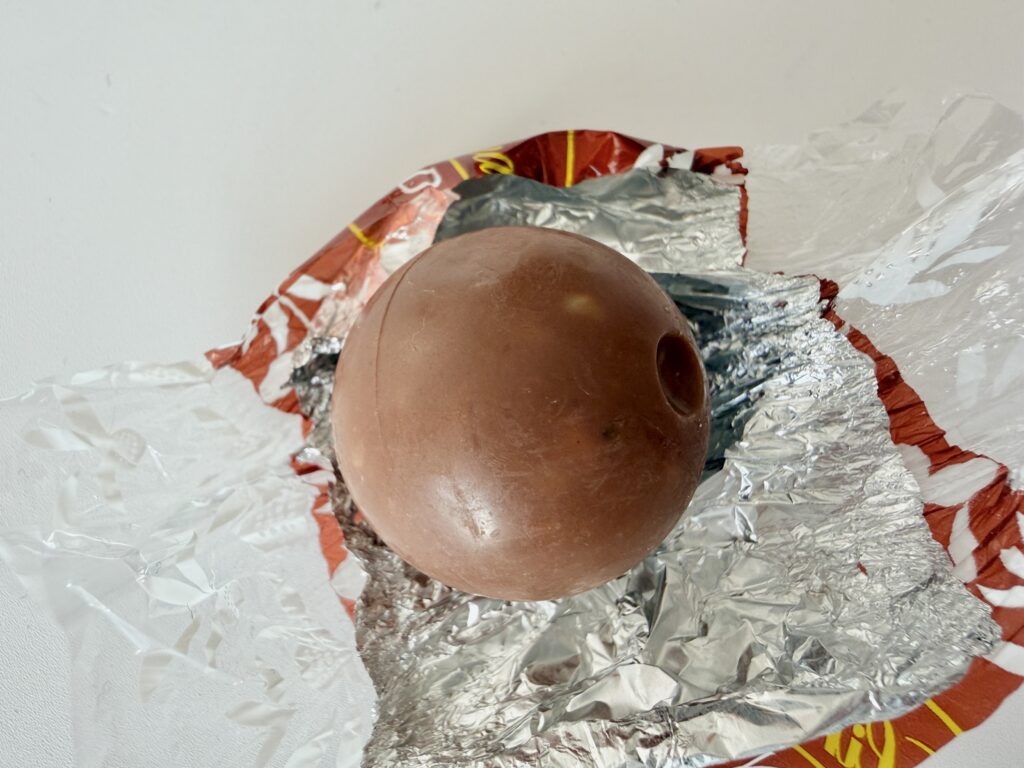 包みを開いたリンツ リンドール ヘーゼルナッツの丸いチョコレート。