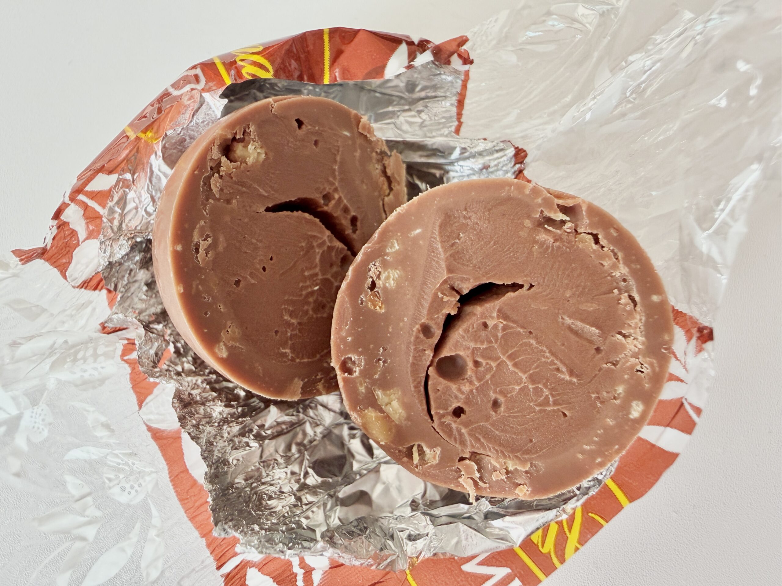 リンツ リンドール ヘーゼルナッツの断面。ミルクチョコレートと滑らかなフィリング、砕きナッツが見える。